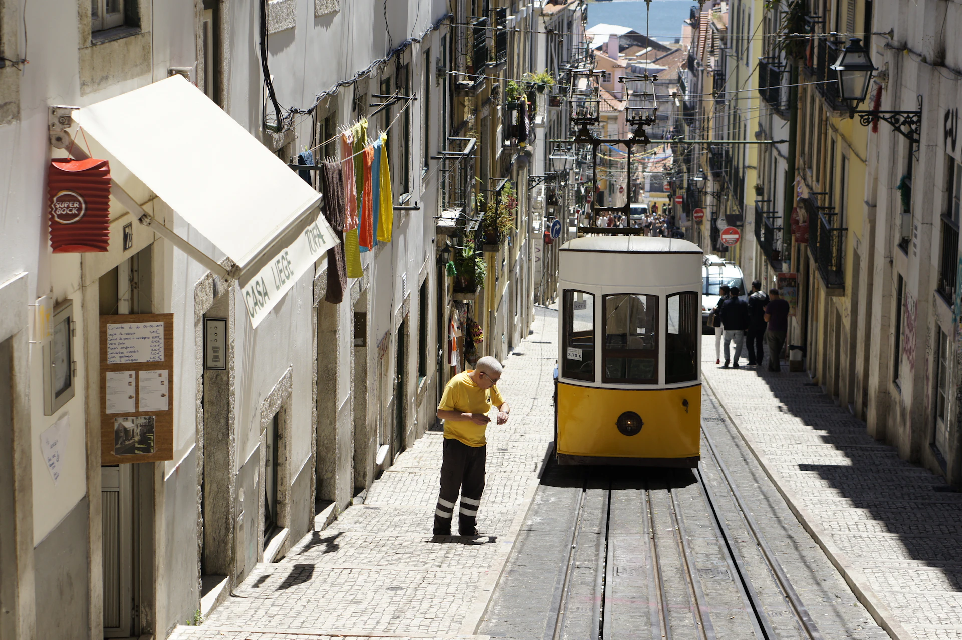 Lisbon yellow tram on a hilly cobbled street