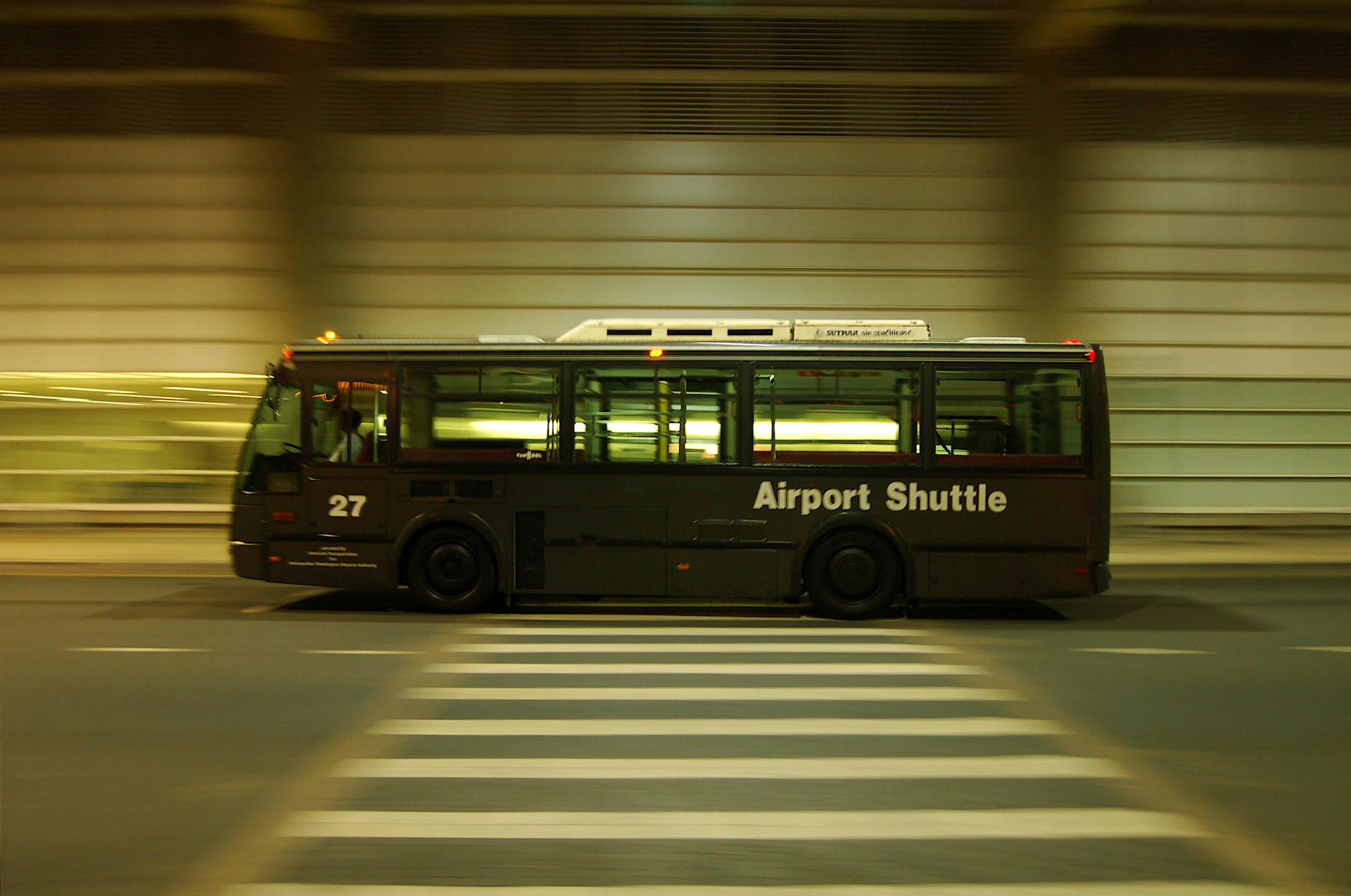 Two cars side by side at airport pickup, a private sedan and a shared shuttle