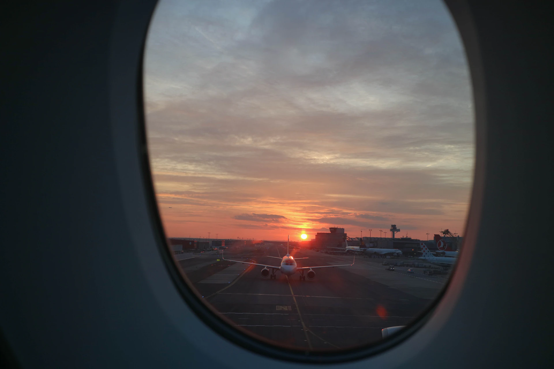 Traveller looking out of an airport window at sunrise